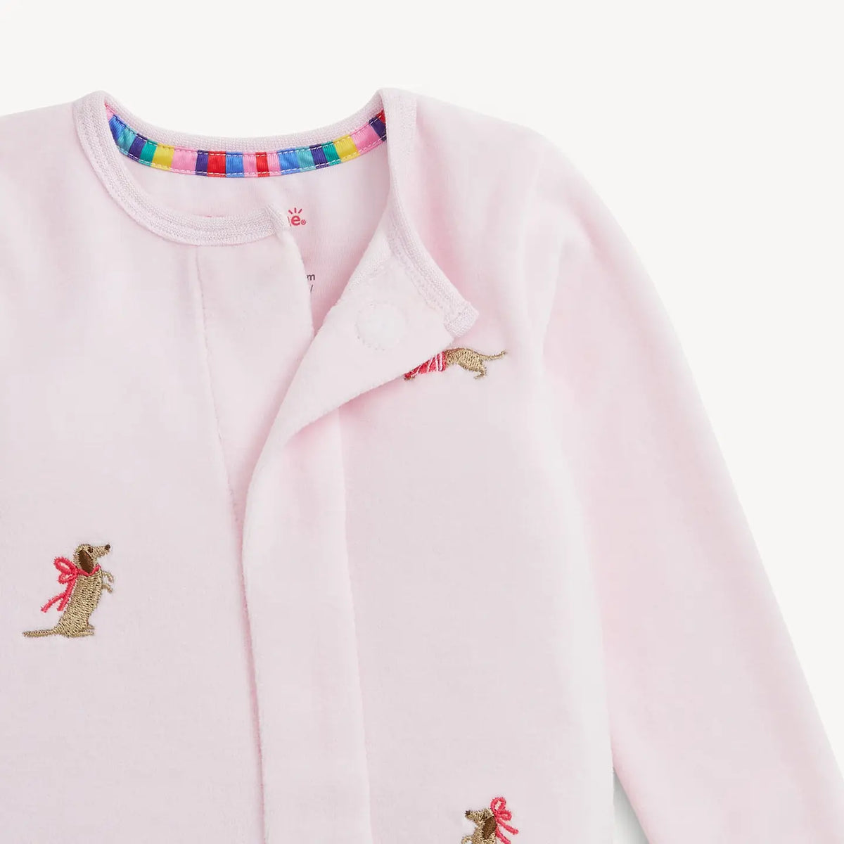 Close-up of the hidden magnetic closures on the pink embroidered dog velour footie.
