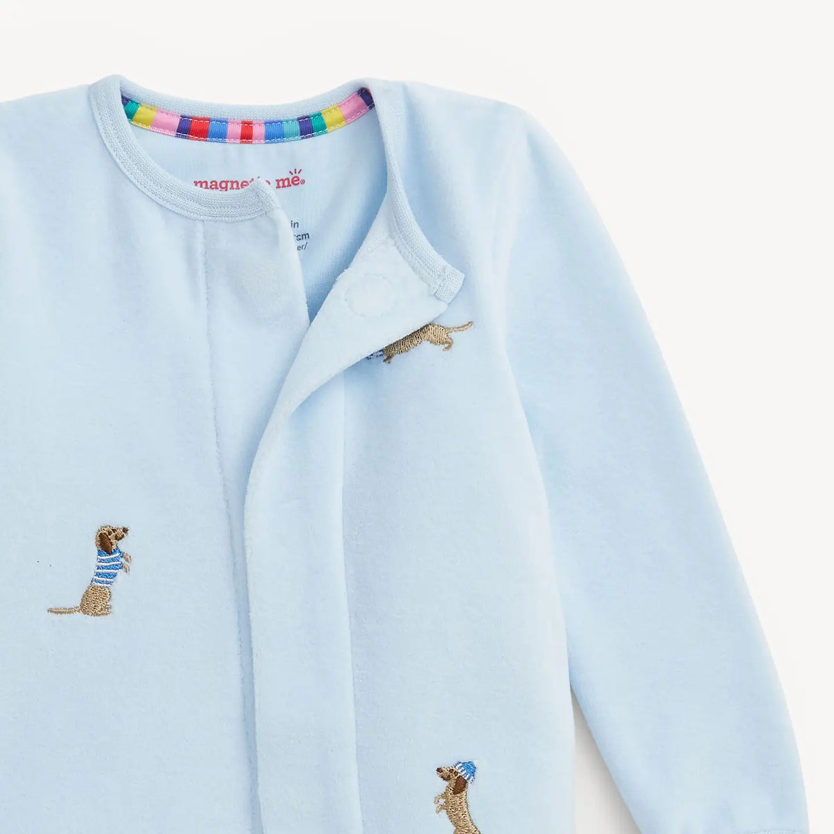 Close-up of the hidden magnetic closures on the blue embroidered dog velour footie.