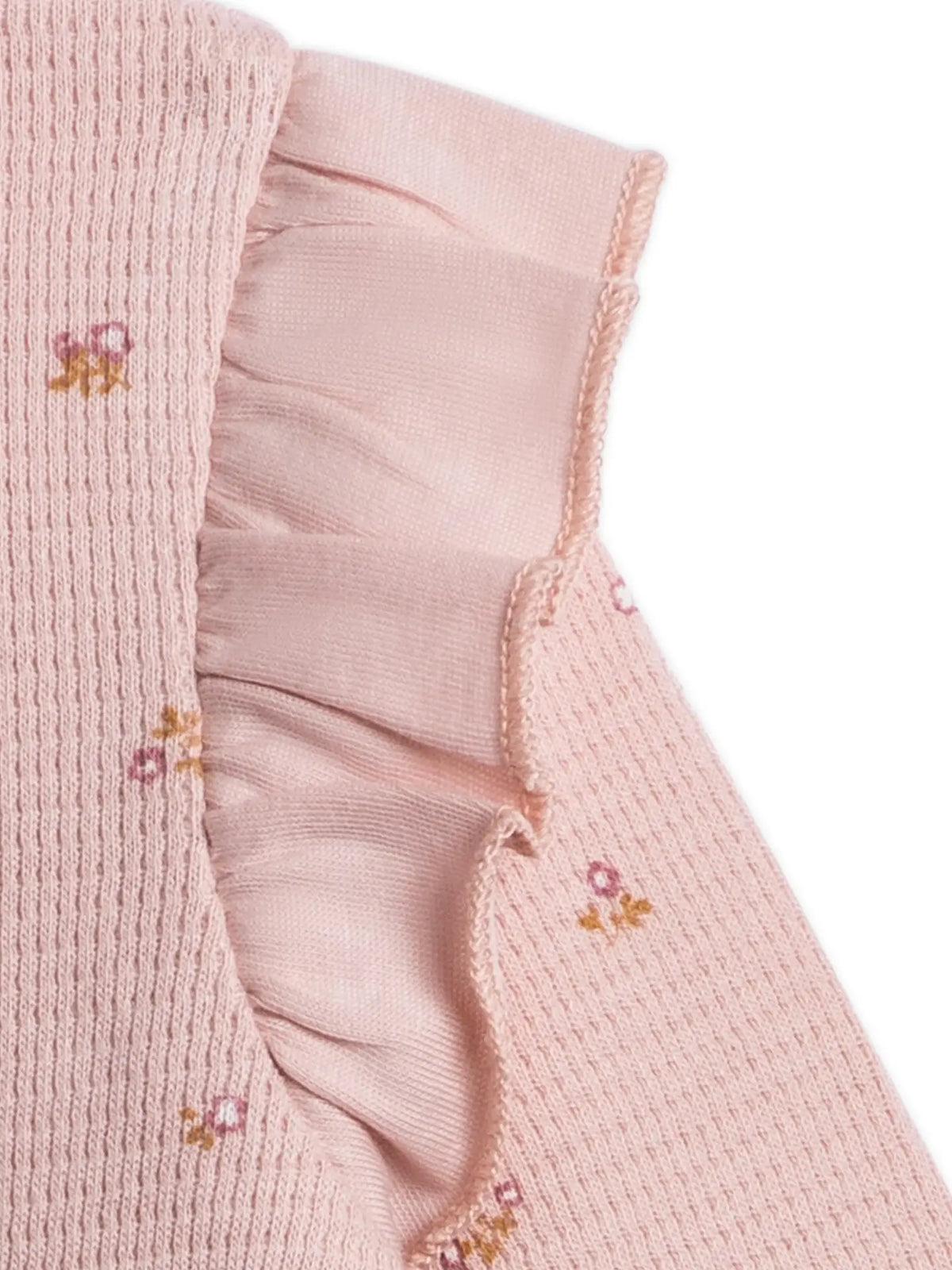 Close-up of the Mila romper’s pink waffle knit fabric, tiny floral print and ruffled shoulder detail.